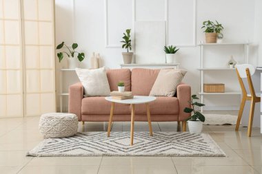 Oturma odasının içinde kanepe, masa ve bitkiler var.