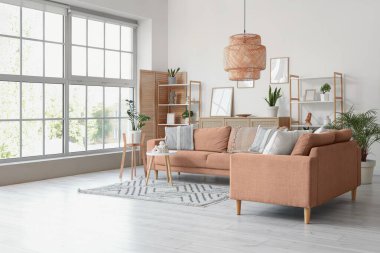 Oturma odasının içinde kanepeler, raf üniteleri ve bitkiler var.