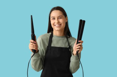 Mavi arka planda saç maşası ve ütüsü olan kadın kuaför.