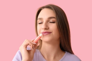 Pembe arka planda dudak kremi olan güzel genç bir kadın.