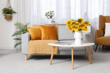 Sehpanın üzerinde ayçiçekleri ve kanepe olan şık bir oturma odası.