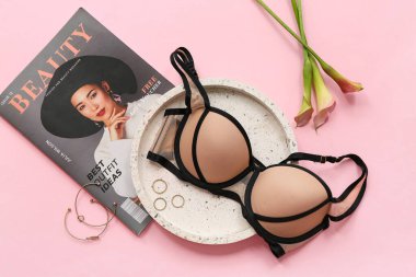 Pembe arka planda şık sütyen, dergi ve aksesuarlı kompozisyon