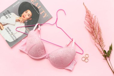 Pembe arka planda şık bayan sütyeni, dergisi ve yüzükleri olan kompozisyon