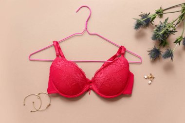 Renkli arka planda şık kırmızı sutyen, aksesuarlar ve bitki dalına sahip kompozisyon