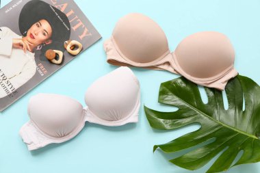 Tarz sahibi bayan sütyenler, küpeler, dergi ve palmiye yaprakları.