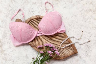 Şık bayan sütyeni, kolye ve açık arkaplanda çiçekli kompozisyon