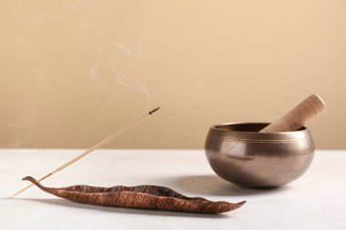 Yanan tütsü çubuğu ve arka planda Tibet şarkı kasesi olan tutucu.