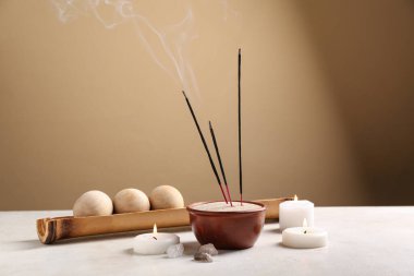 Yanan tütsü çubukları, yanan mumlar ve renkli duvarlara karşı masa üzerinde ahşap masaj topları.