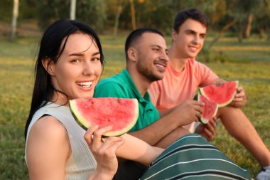Gün batımında parkta piknik yapan karpuz dilimli genç bir kadın, yakın plan.