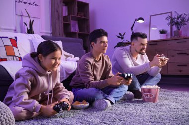 Baba ve çocukları akşam evde video oyunu oynuyorlar.