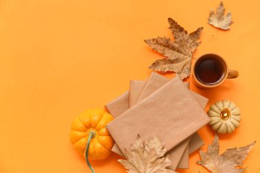 Kitaplı kompozisyon, çay fincanı, balkabağı ve sonbahar yapraklı renk arkaplanı