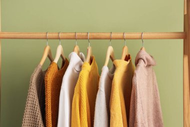 Soyunma odasındaki yeşil duvarın yanında kazaklarla dizilin.