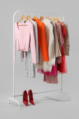 Gri arka planda şık kadın kıyafetleri ve topuklu ayakkabılar var.