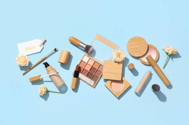 Renkli arka planda farklı dekoratif kozmetik ürünleri, satış etiketi ve çiçeklere sahip kompozisyon