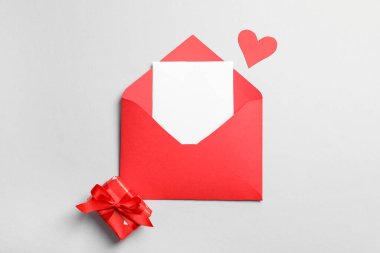 İçinde boş kart, kağıt kalp ve gri arka planda hediye kutusu olan bir zarf. Sevgililer Günü kutlaması
