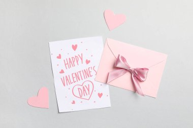 İçinde hediye kartı ve gri arka planda kağıt kalpler olan zarf. Sevgililer Günü kutlaması
