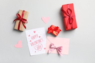 İçinde hediye kartı, kutular ve gri arka planda kağıt kalpler olan zarf. Sevgililer Günü kutlaması