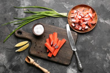 Ahşap tahta ve tabakta siyah arka planda lezzetli yengeç çubukları var.