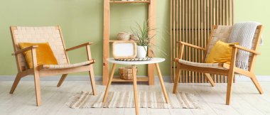 Rahat koltukları, raf ünitesi ve yeşil duvarın yanındaki masa olan modern odanın içi.