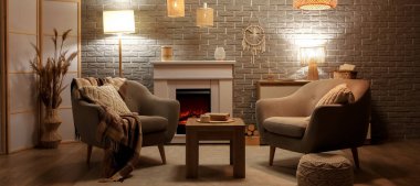 Geceleri şömineli, koltuklu ve parlayan lambalı rahat bir oturma odası.