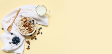 Bir kase çiğ yulaf ezmesi, fındık, böğürtlen ve süt renkli arkaplanda metin ve üst görünüm için boşluk