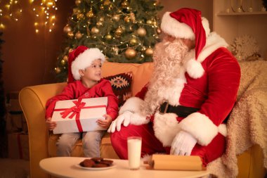 Noel hediyesi olan şirin küçük bir çocuk ve evde Noel Baba.