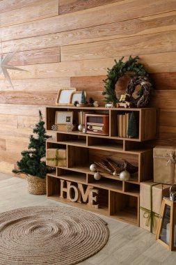 Kaliteli radyosu, kitapları ve Noel süslemeleri olan raf ünitesi ahşap duvarın yanında.