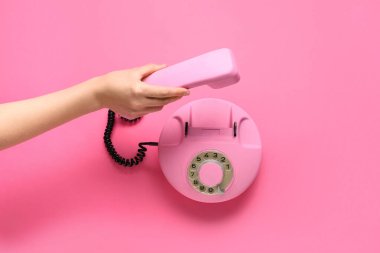 Pembe arka planda retro telefonu olan bir kadın.