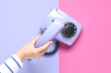 Arka planda leylak retro telefona sahip bir kadın el.