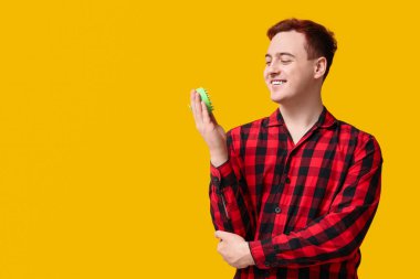 Sarı arka planda saç derisi masaj aleti olan genç bir adam.