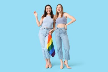 Mavi arka planda LGBT bayrağı olan güzel bir lezbiyen çift.