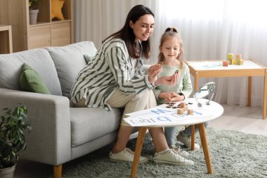 Ofiste küçük bir kızla çalışan kadın konuşma terapisti.