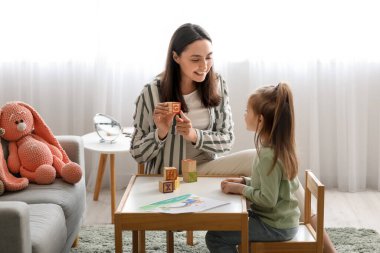 Küpleri ve küçük kızı olan kadın konuşma terapisti.