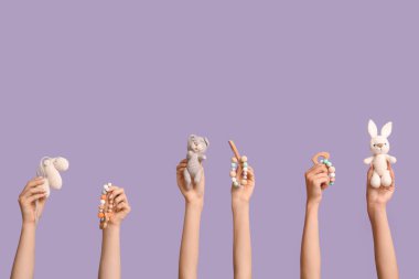 Bebek iple bağlanmış kadın elleri ve leylak arka planda örülmüş oyuncaklar.