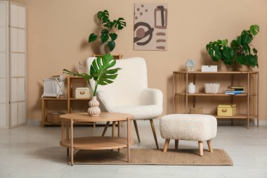 Masada ve şık koltukta tropikal canavar yaprakları olan modern bir oturma odası.