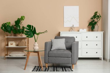 Masada ve şık koltukta tropikal canavar yaprakları olan modern bir oturma odası.