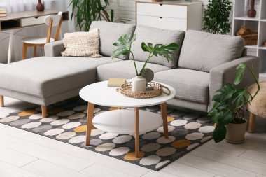 Masada ve şık koltukta tropikal canavar yaprakları olan modern bir oturma odası.