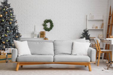 Oturma odasının içinde kanepe, Noel ağaçları ve hediyeler var.