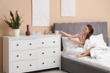 Yatağında çay olan genç ve güzel bir kadının sabahı.