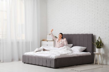 Güzel genç bir bayanın yatağında oturup esnediği bir sabah.