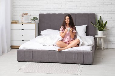 Yatağında çay olan genç ve güzel bir kadının sabahı.