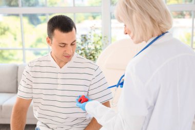 Tiroid bezi modelini klinikteki erkek hastaya gösteren kadın endokrinolog.