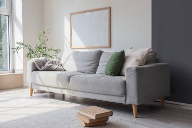 Gri kanepeli, çiçekli ve duvarında büyük çerçeveli şık bir oda.