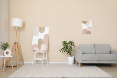 Oturma odasının içinde resimler, kanepe ve lamba var.