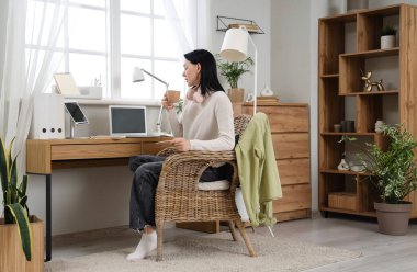 Ofisteki masada oturan bir fincan kahveyle genç bir kadın.