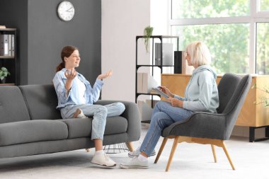 Gülümseyen genç kız ofiste psikologla konuşuyor.