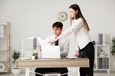 Genç işadamı belgelerle ve kadın meslektaşıyla birlikte çalışıyor.