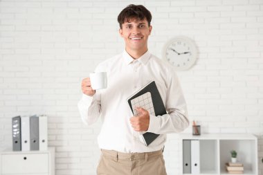 Ofisinde kahve fincanı ve defterleri olan yakışıklı bir iş adamı.