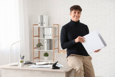 Handsome businessman with folder in office