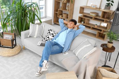 Evdeki kanepede klimalı yakışıklı genç adam dinleniyor.